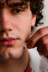 using acne pimple patch to clean the face from zits. young man uses acne stickers as bandage not to 