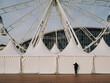 © Jordi Huisman - A person looks through the curtain of a event tent next to a ferris wheel