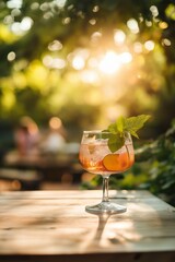 Wall Mural - A glass of pink drink with a sprig of mint on top. The drink is on a table in a park