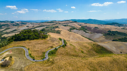 An aerial view of L'Anello near Volterra in Tuscany, Italy, captured by a drone. This scenic area is known for its lush, rolling hills and picturesque landscapes typical of the Tuscan region