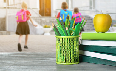 Poster - Holder with stationery, books and apple on wooden table against white background