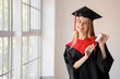 © Pixel-Shot - Female graduate student with diploma near window in room