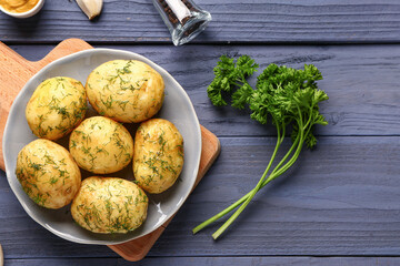 Plate of boiled baby potatoes with dill and parsley on blue wooden background