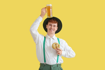 Sticker - Young man in traditional German clothes with beer and pretzel on yellow background