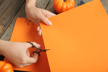 Wall Mural - Woman cutting wrapping paper for Halloween gifts on brown wooden background