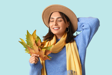 Poster - Beautiful young woman with autumn leaves on blue background