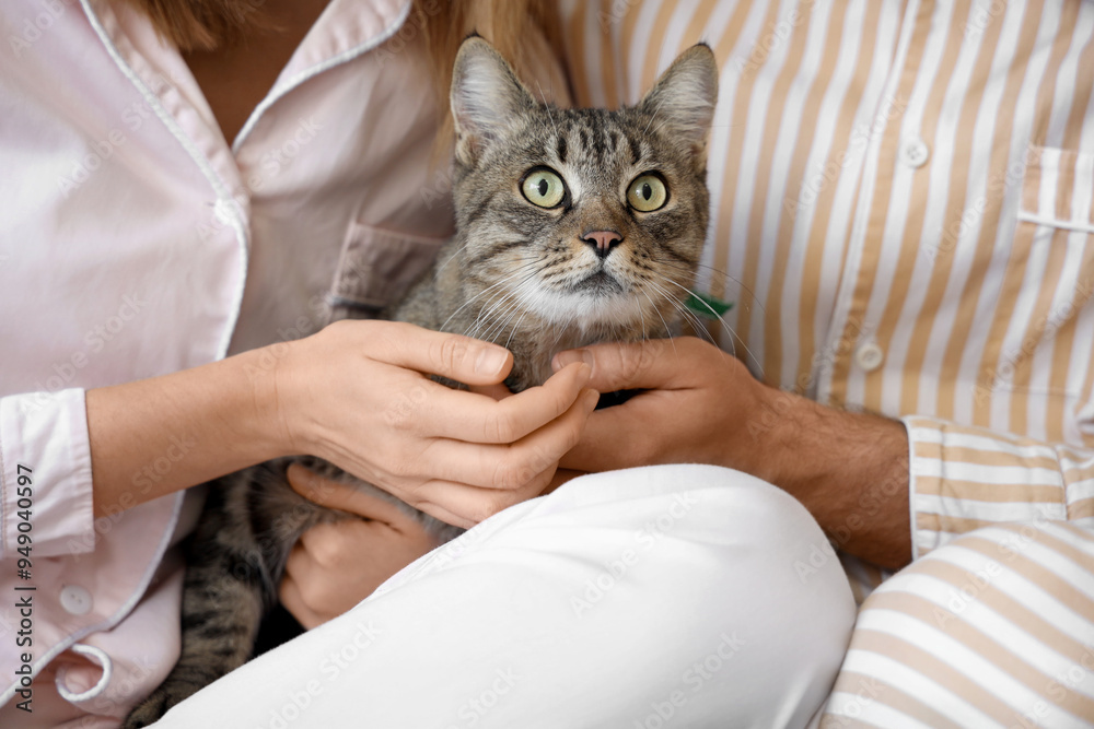 Young couple with cute cat in bedroom, closeup
