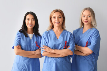 Wall Mural - Professional team of doctors with red ribbons on grey background. World AIDS Day concept