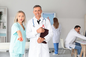 Sticker - Professional doctors with red ribbons in clinic. World AIDS Day concept