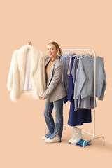 Sticker - Female stylist with clothes on rack against beige background