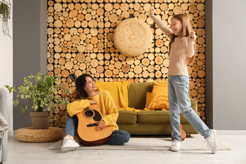 Canvas Print - Girl dancing to young woman playing guitar at home