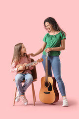 Wall Mural - Young woman and girl with acoustic guitars on pink background