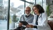 © Loki Stock - Elderly male patient smiling while discussing with young female doctor holding a tablet in a bright, modern medical office