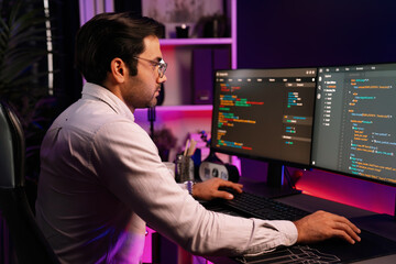 Working smart IT developer analyzing data software development on two pc screen, creating application program updated version online website page system online at neon light cyber office. Surmise.