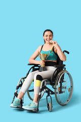 Poster - Sporty young woman in wheelchair with first place medal and gold cup on blue background