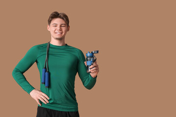 Poster - Sporty young man with bottle of water and jumping rope on brown background