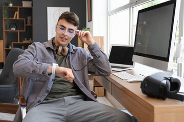 Poster - Young man checking smartwatch at desk in office