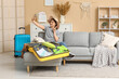 © Pixel-Shot - Young woman in hat taking selfie with mobile phone near suitcase on sofa at home. Summer travel concept