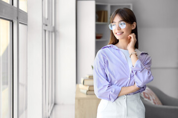 Wall Mural - Young woman in eyeglasses near window at home