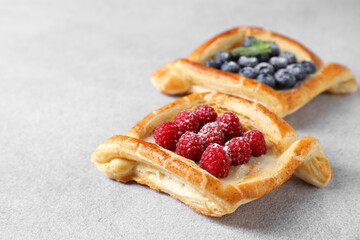 Wall Mural - Tasty puff pastries with berries on white table, closeup. Space for text