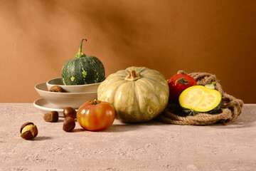 Close up shot on cement table containing variety autumn vegetables in the center consist of pumpkin, tomato and chestnut. Advertising photo from front view, designing space