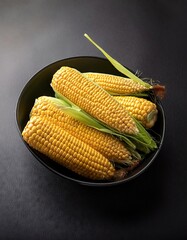 Wall Mural - Corn in a bowl on a black background, top view, copy space 