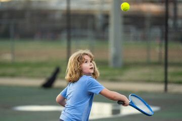 Canvas Print - Kid play tennis. Little kid hit tennis ball with tennis racket. Active exercise for kids. Summer activities for children. Child learning to play tennis. Sport Kid hitting Ball on court.