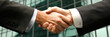 © Xingguo - Close-up shot of two business people in formal wear shaking hands with a blurred busy office environment in the background, symbolizing a partnership