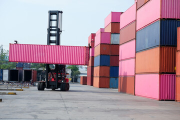 Container forklift lifting in shipping yard with stack of containers, copy area, logistics, import, export of freight forwarders and transportation industry concept.