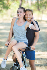 active young couple biking on a forest