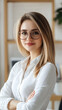 © solom - Portrait of a young, beautiful blonde woman in a white shirt and glasses, standing with her arms crossed and looking at the camera with a smile