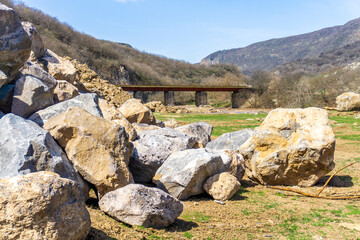 Sticker - Huge stones in the meadow. Iron bridge over the river in the gorge. Mountains in the background