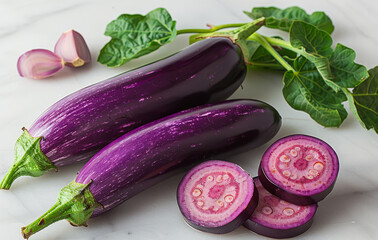 Fresh purple eggplants with garlic on a marble counter. Two vibrant purple eggplants are accompanied by garlic cloves and leafy green tops, arranged neatly on a marble countertop.