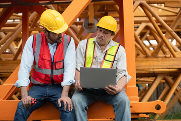 Wall Mural - Asia engineer man worker use tablet computer and India engineer man use walkie talkie working with crane spare part background	