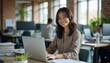 © AlgoVijo - Young Woman Smiling While Working on Laptop in Modern Office Space
