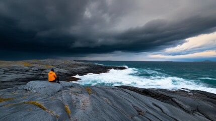 Isolated person sitting on a rocky shore