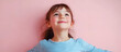 © john - A joyful young girl in a blue striped shirt poses for a studio portrait on a plain pastel pink background embodying a carefree childhood lifestyle with copy space image