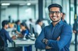 © Zaleman - Standing with his arms crossed in a modern office for an IT company, a smiling Indian businessman smiles
