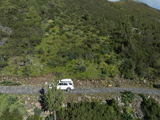 Aerial view of offroad car running in high altitude mountains landscape