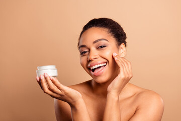 Poster - Photo of gorgeous cheerful woman apply cream face naked shoulders isolated on beige pastel color background