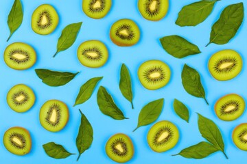 Wall Mural - Vibrant kiwi slices with green leaves on blue background