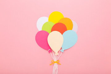 Wall Mural - Bunch of colorful balloon shapes from application paper with white strings and ribbon on light pink table background. Pastel color. Closeup. Top down view.