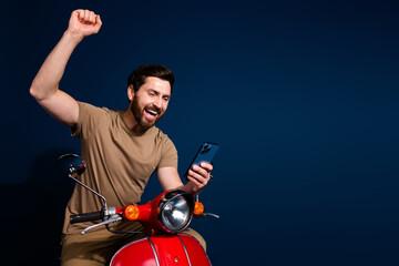 Canvas Print - Photo of happy young man in beige t shirt likes summertime riding motorbike celebrate approved for date isolated on dark blue color background