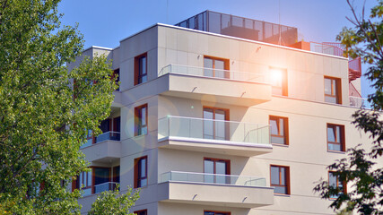 Wall Mural - A apartment building with a lot of balconies and windows. The building is surrounded by trees and has a lot of greenery. Green surroundings of buildings. Ecological housing estate.