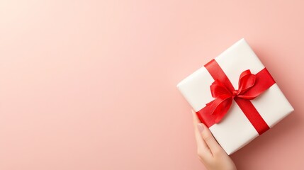 A festive gift box wrapped with a red ribbon, perfect for celebrations, birthdays, and special occasions on a soft pink background.