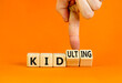© Dzmitry - Kid or kidulting symbol. Concept words Kid or Kidulting on wooden cubes. Beautiful orange table orange background. Psychologist hand. Healthy lifestyle and kid or kidulting concept. Copy space.