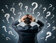 © luis - The back of a stressed european businessman with chalk drawn question marks on a blackboard background. A solution, education, and knowledge concept.