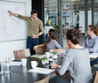 © ArcursForPI/peopleimages.com - Businessman, whiteboard and presentation with team in meeting for company steps, mission or workflow at office. Man or speaker talking to employees with graph or chart for work structure in boardroom