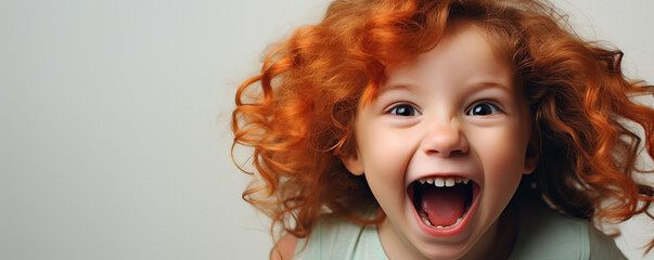 Wall Mural - Excited child with curly red hair displaying pure joy in a bright studio setting