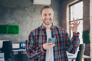 Canvas Print - Photo of nice young man company worker smart phone okey symbol wear checkered shirt modern loft office indoors